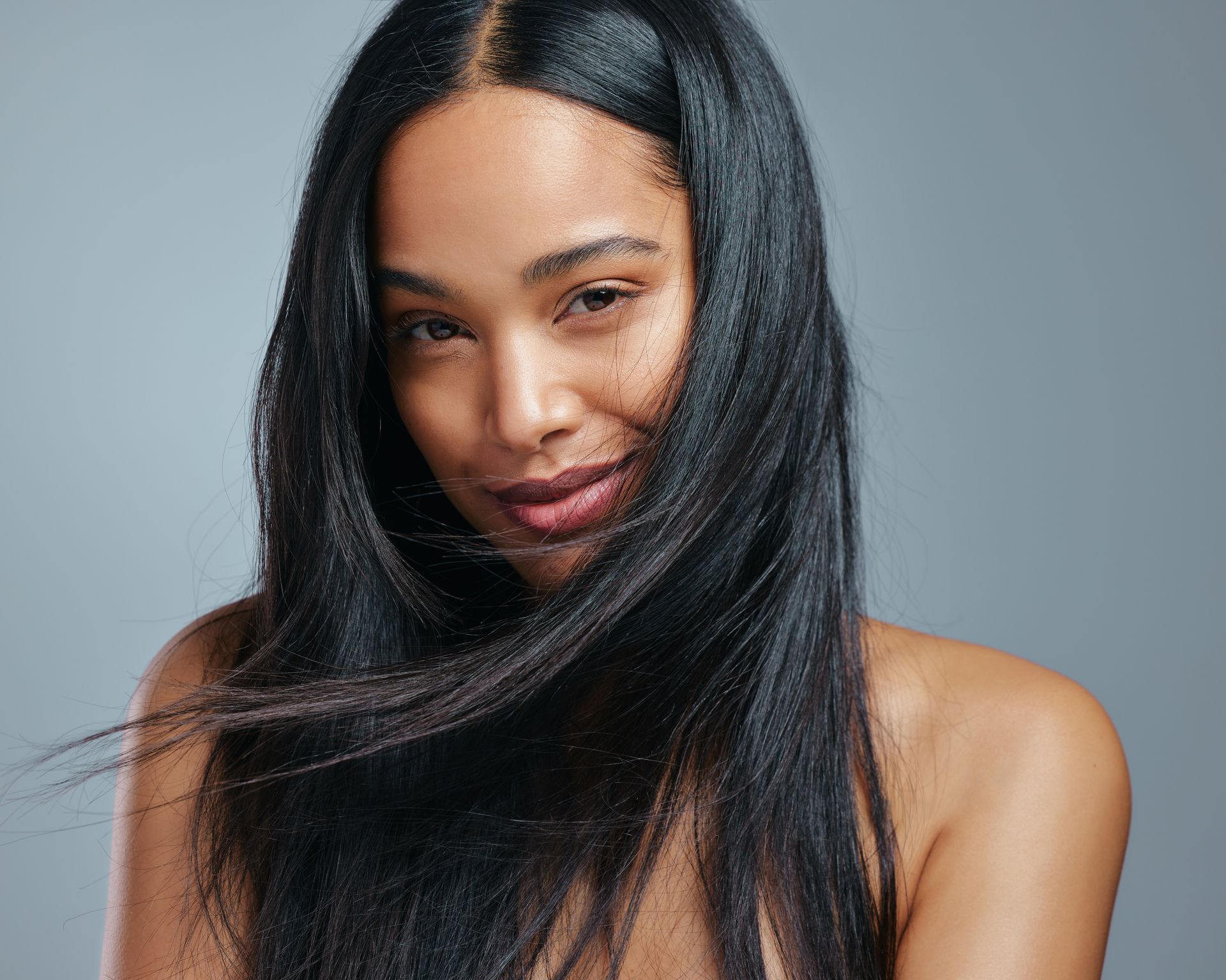 A woman with long black hair is smiling and looking at the camera.