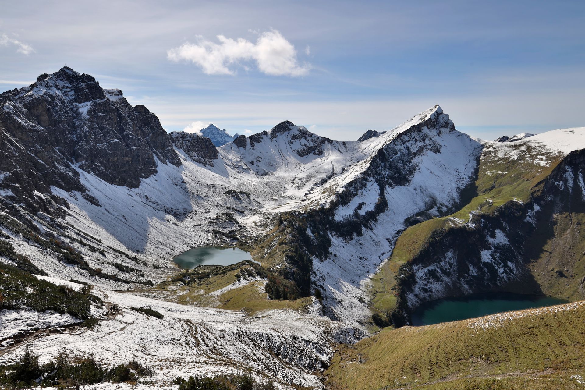 Schneebedeckte Berggipfel mit zwei türkisfarbenen Seen darunter, unter klarem Himmel.