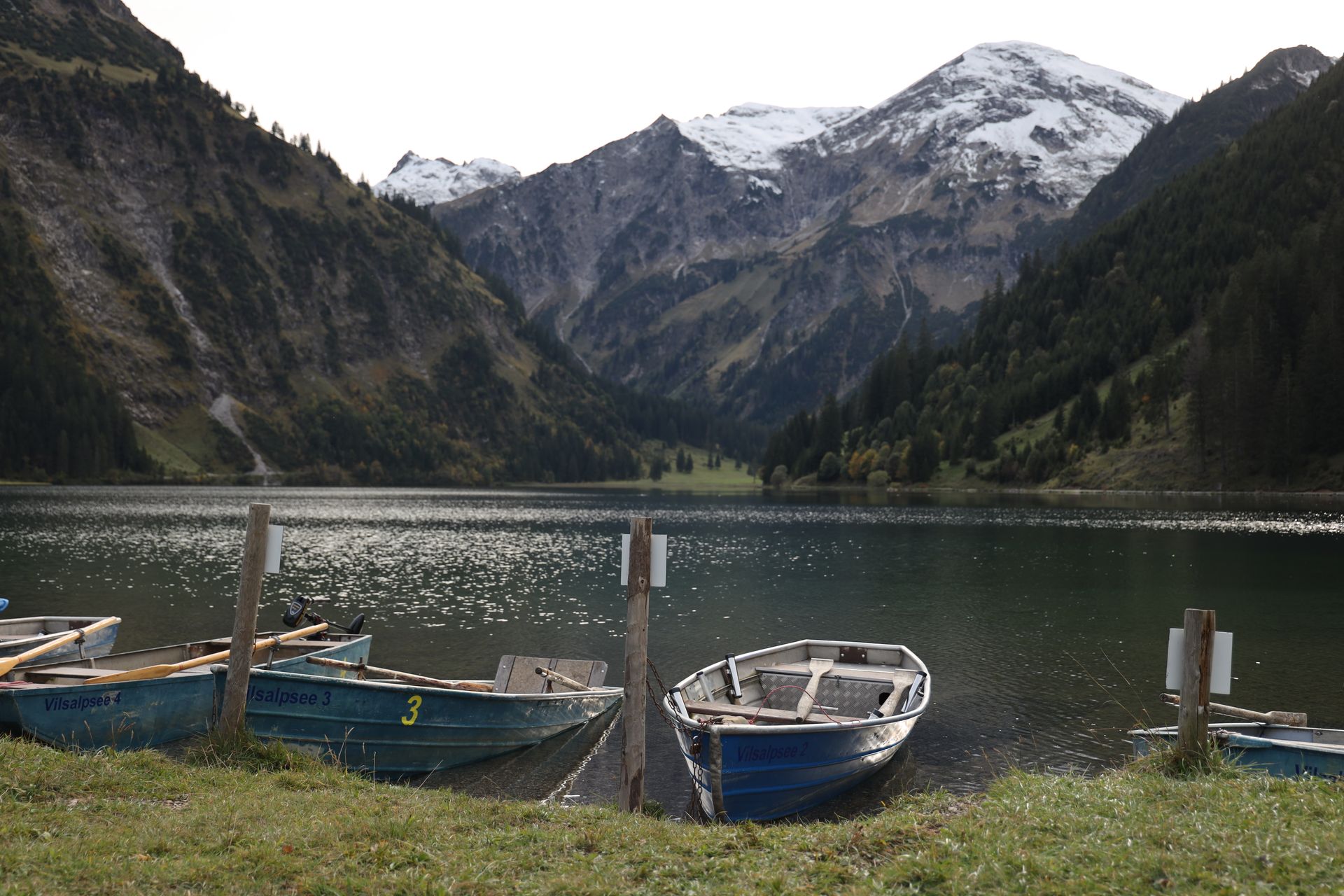 Eine Reihe von Booten auf einem See mit Bergen im Hintergrund