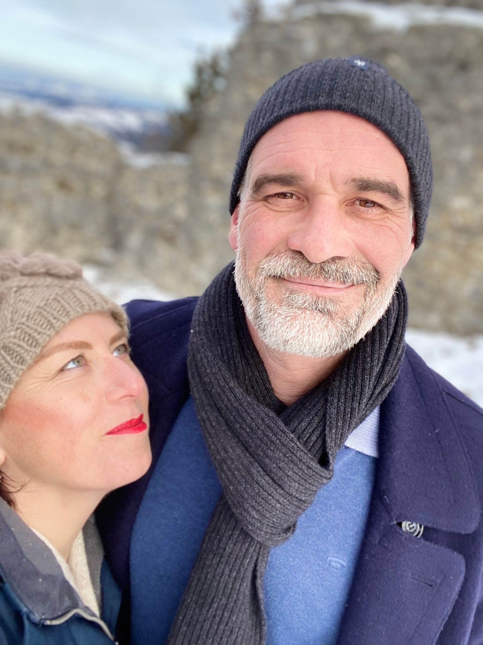 Ein Mann mit Bart und Schal steht neben einer Frau im Schnee.