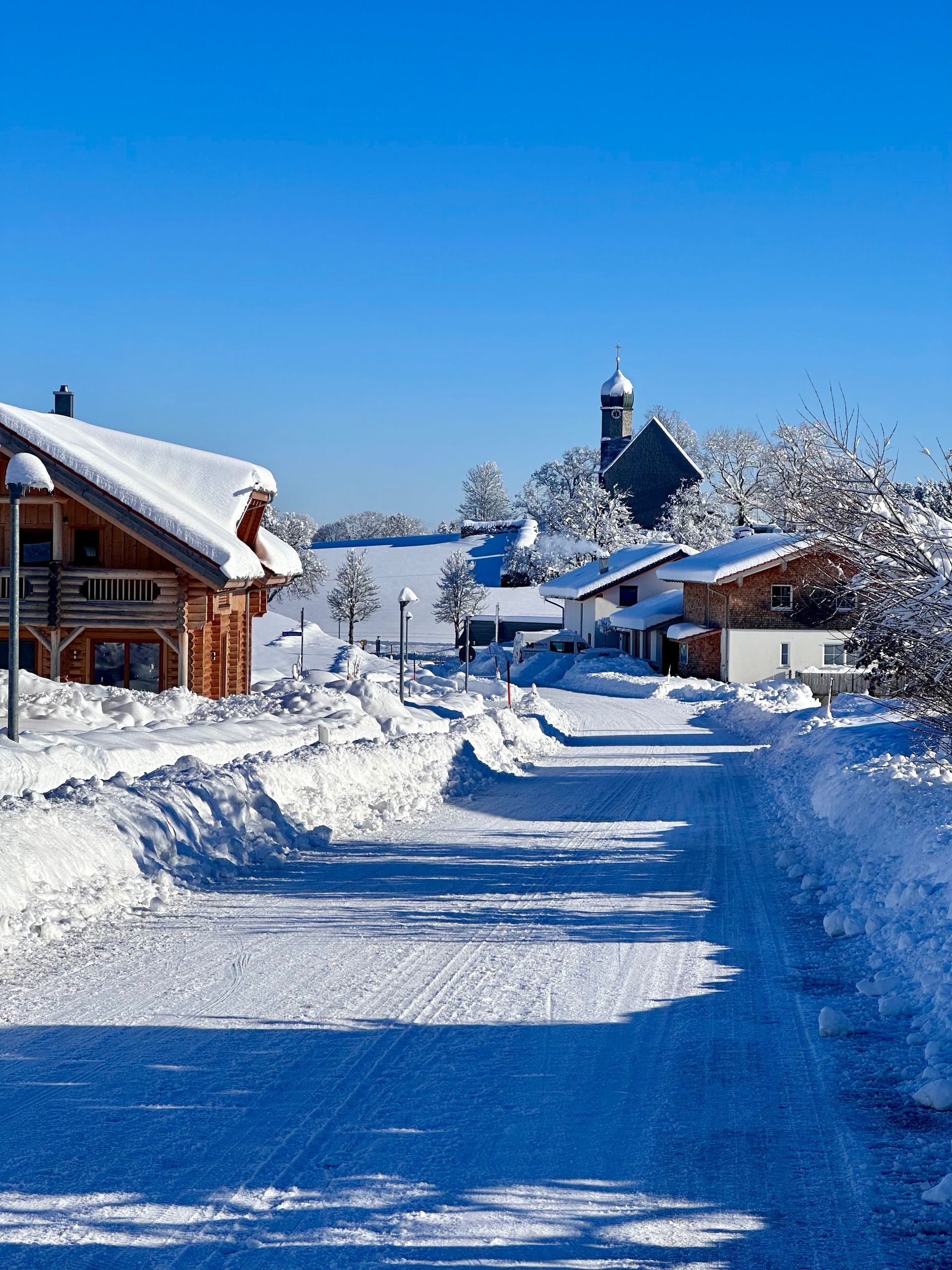 Ein verschneites Dorf mit einer Kirche im Hintergrund