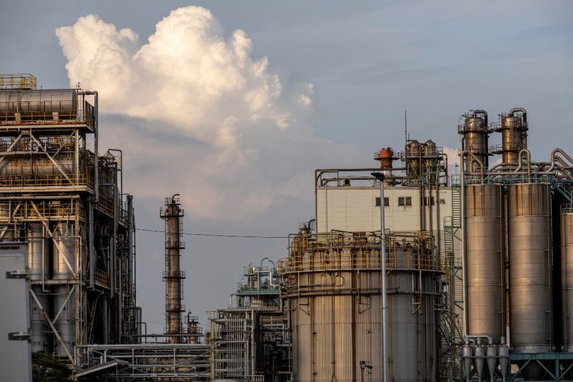 Industrial refinery structures against a cloudy sky.