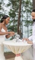 Couple signing a marriage certificate at a small table outdoors by the beach
