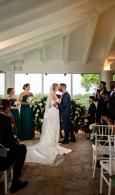 Bride and groom exchange vows in a white tent aisle at a wedding ceremony