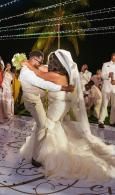 Bride and groom dancing closely at an outdoor wedding reception under string lights