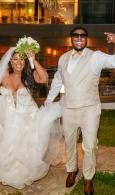 Bride and groom in white wedding attire smiling and dancing outdoors at night