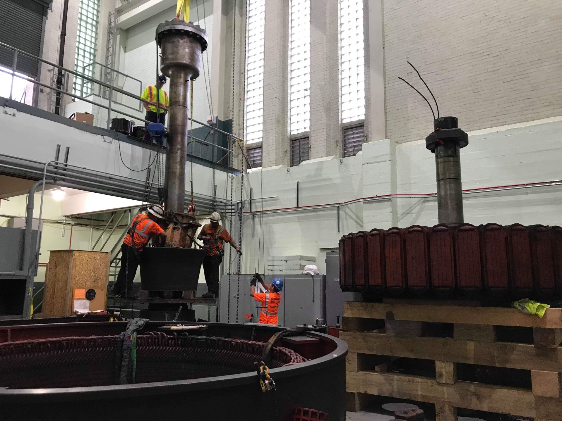 Workers assembling machinery inside a large industrial building.