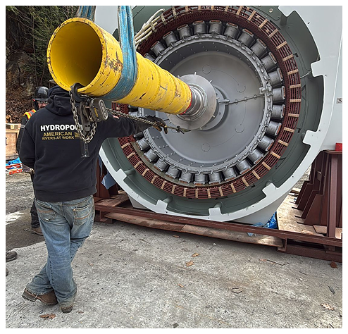 Man in black hoodie, next to a large industrial generator, being installed outdoors.