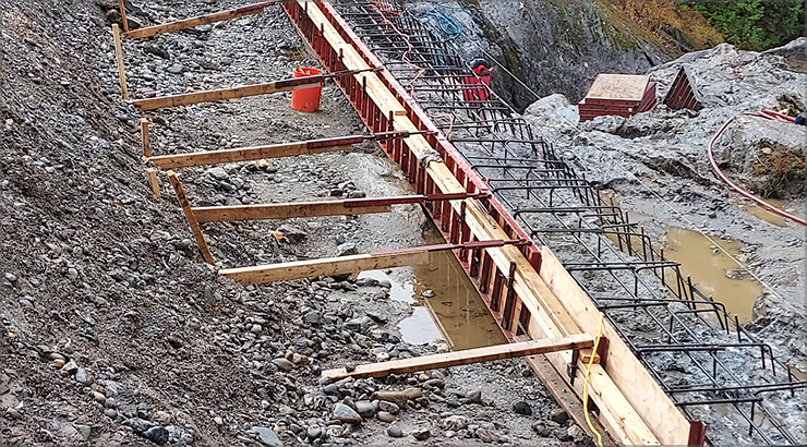 Construction site: concrete formwork built into a hillside, rebar exposed, wooden supports.
