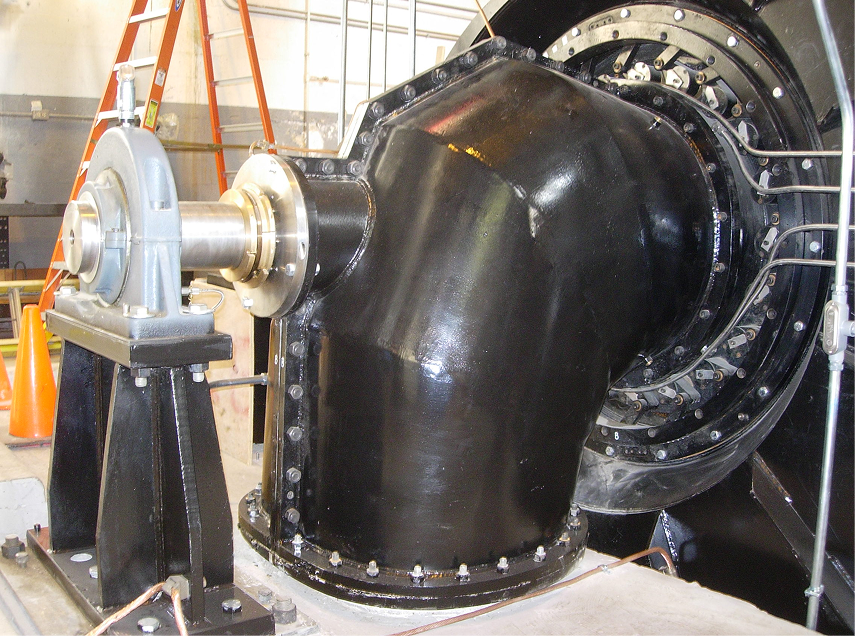 Black industrial machinery, angled pipe and large wheel, mounted on black supports, indoor setting.