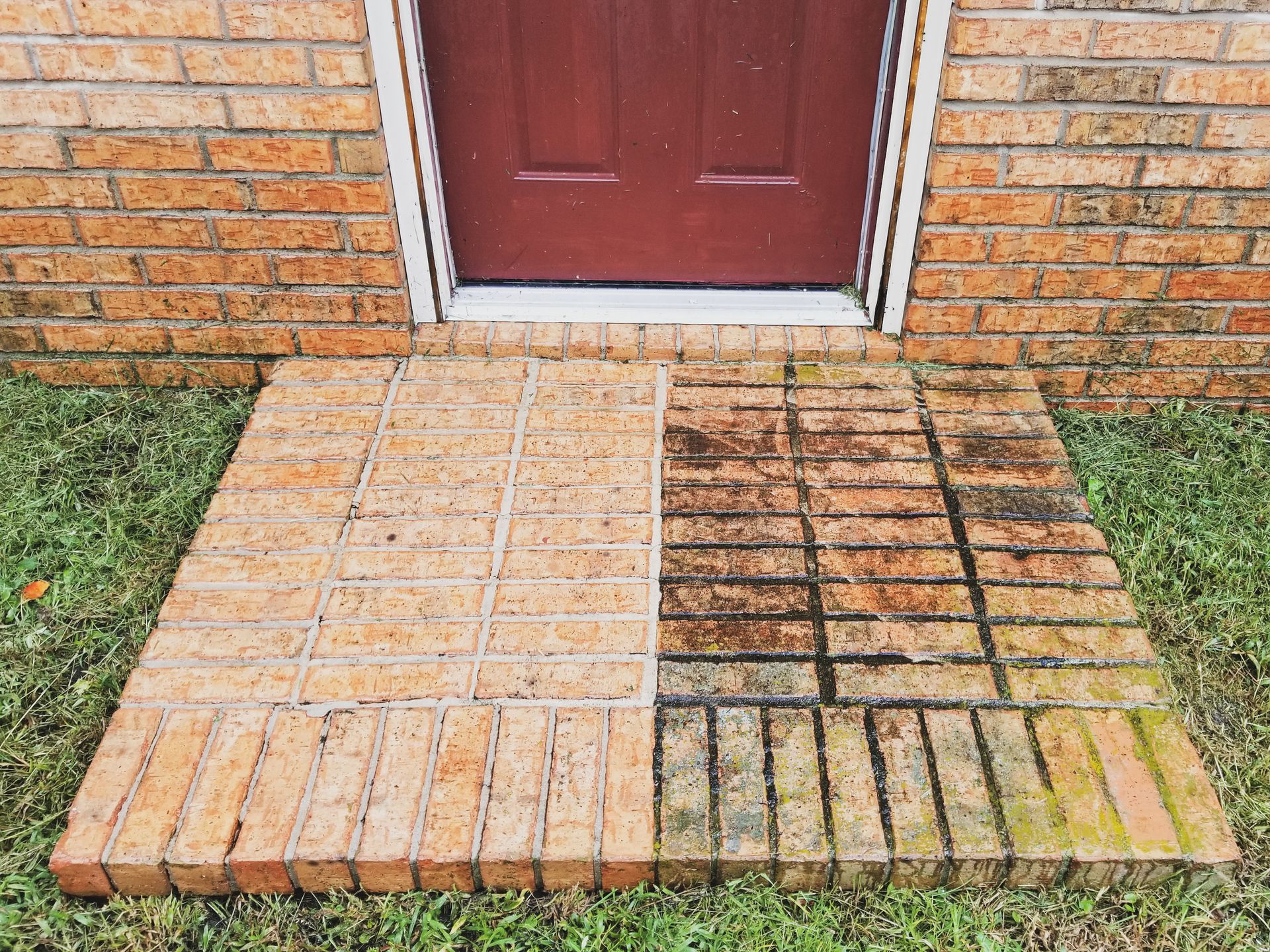 Brick ramp and steps leading to a red front door with a partially tiled walkway and brick wall