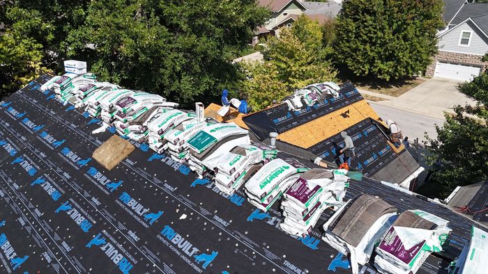 Roofers in Indianapolis are working on a residential roof covered in underlayment.