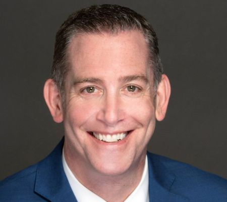 Smiling man in blue suit, looking at the camera.