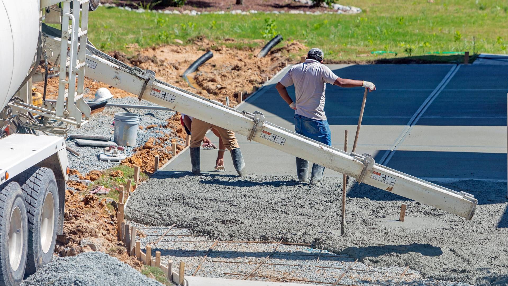 A couple of men are working on a concrete driveway.