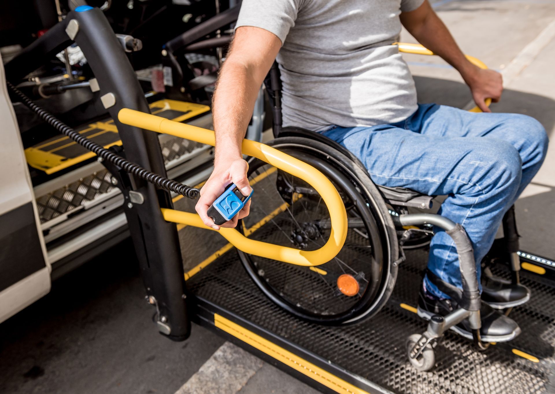 A person in a wheelchair using a lift to enter a van. The ramp is black with yellow safety rails.
