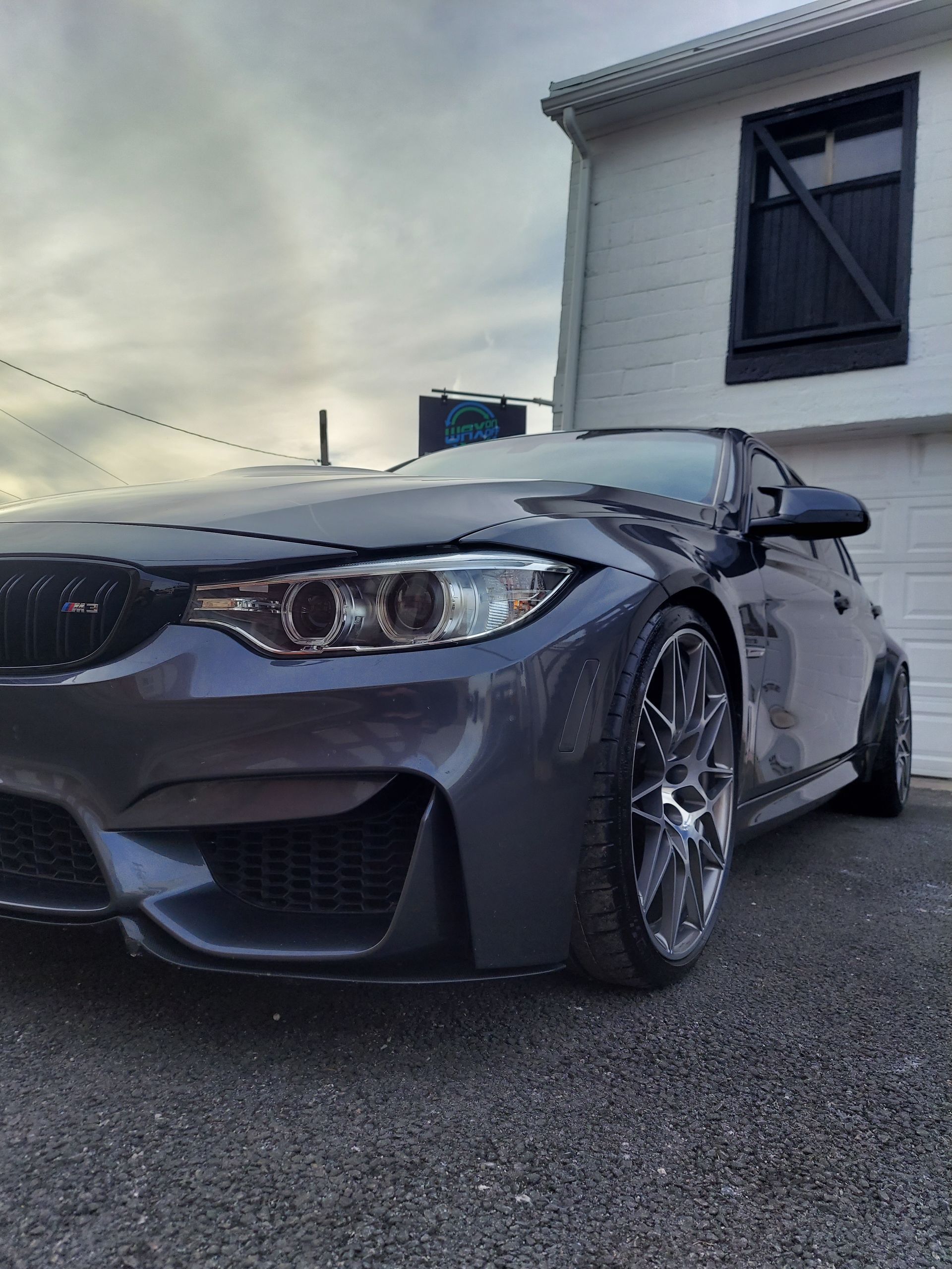 Gray BMW sports car parked in front of a white building with black window shutters.