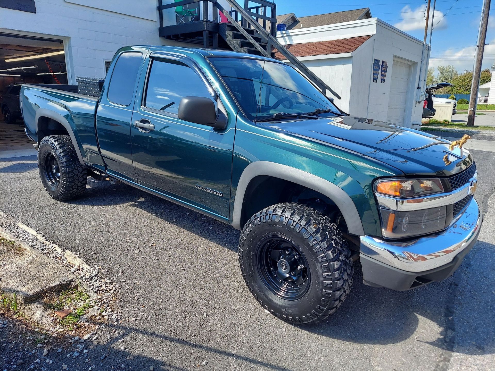 Green Chevrolet Colorado pickup truck, black wheels, parked on pavement.