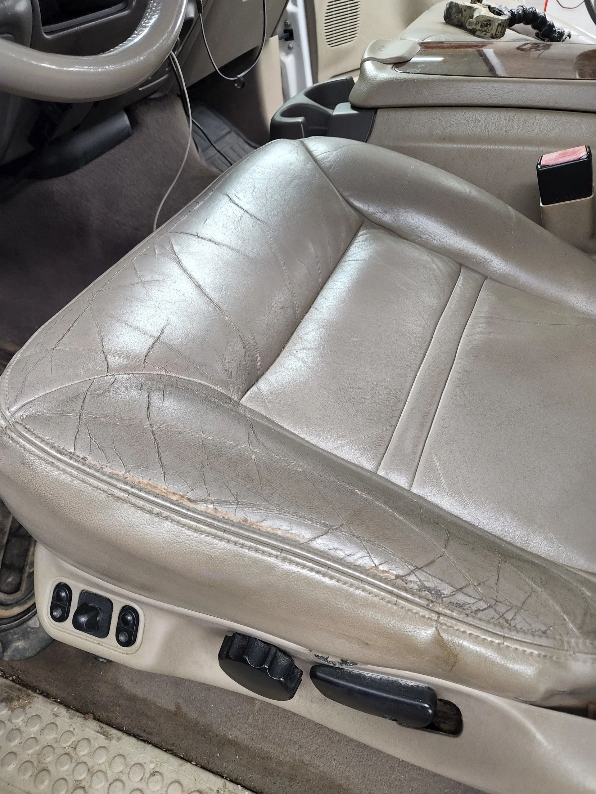 Tan leather car seat with significant wear and cracks.