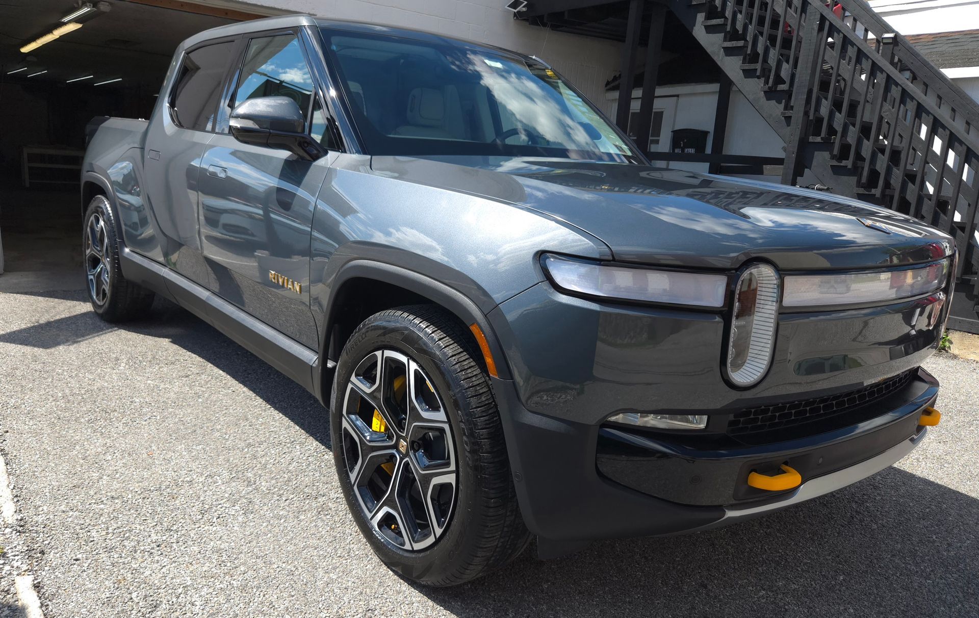 Gray Rivian electric pickup truck parked outdoors, with black and yellow accents.