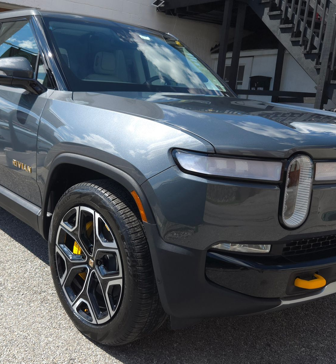 Gray Rivian electric SUV parked outdoors. Yellow brake calipers visible on front tire.