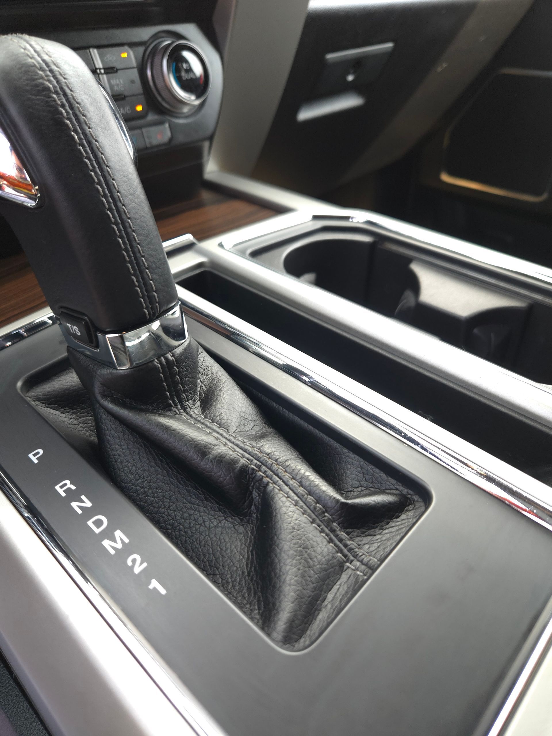 Gear shift lever in a car, with positions P, R, N, D, M, and 1. Silver trim and black leather.