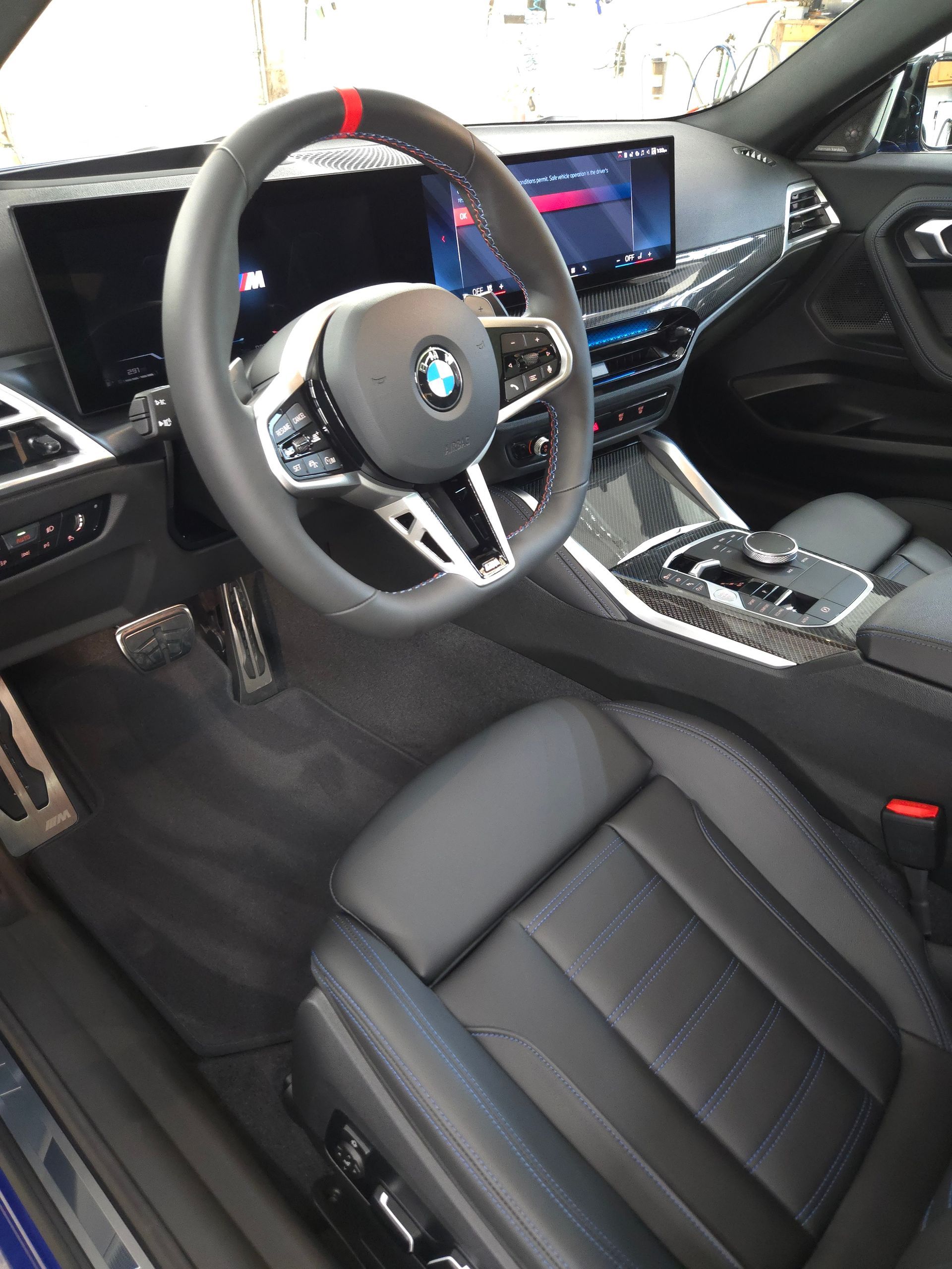 Interior of a black and blue BMW with a steering wheel and dashboard.