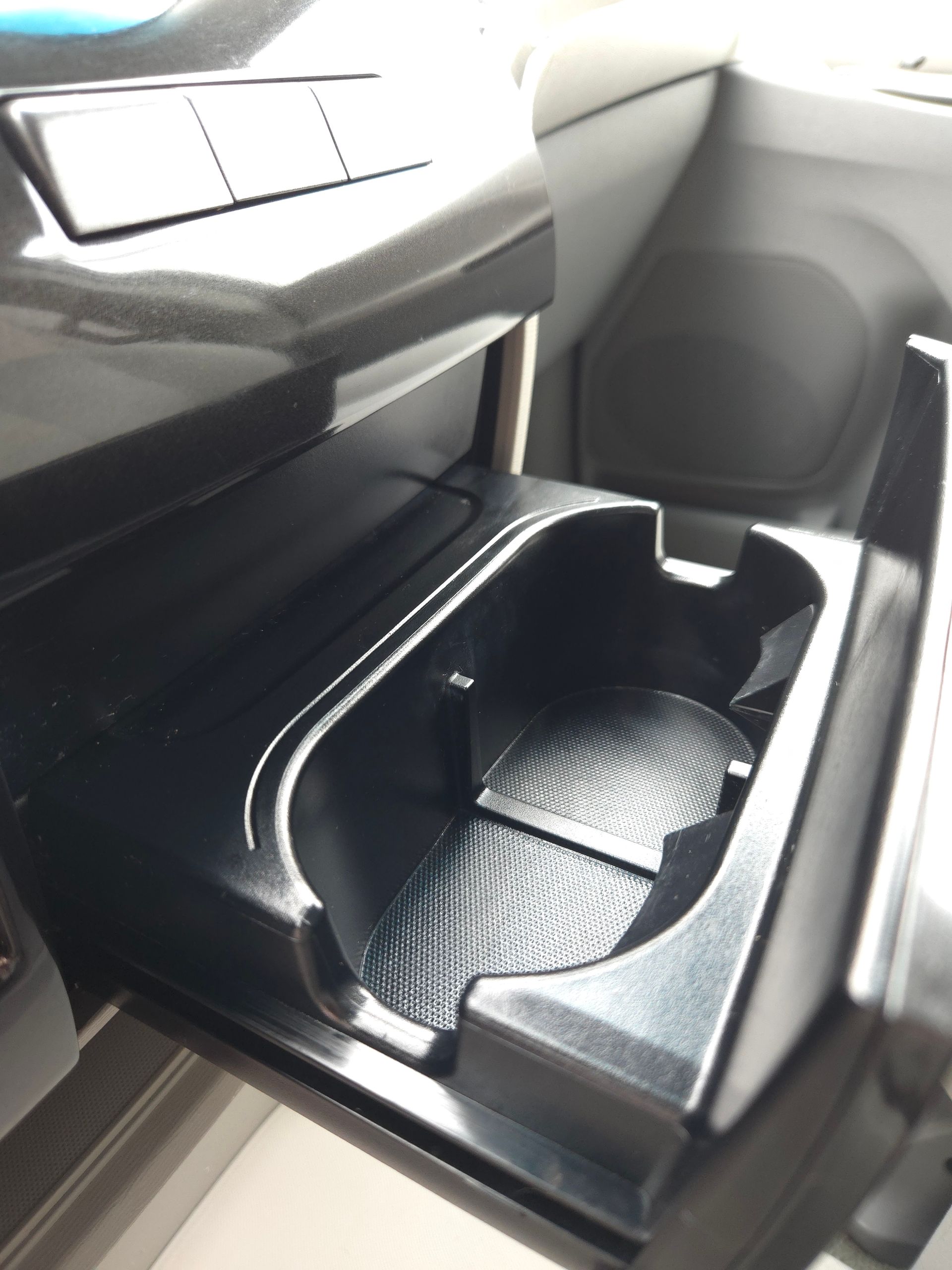 Black car cupholder with a textured bottom, inside a car's center console.