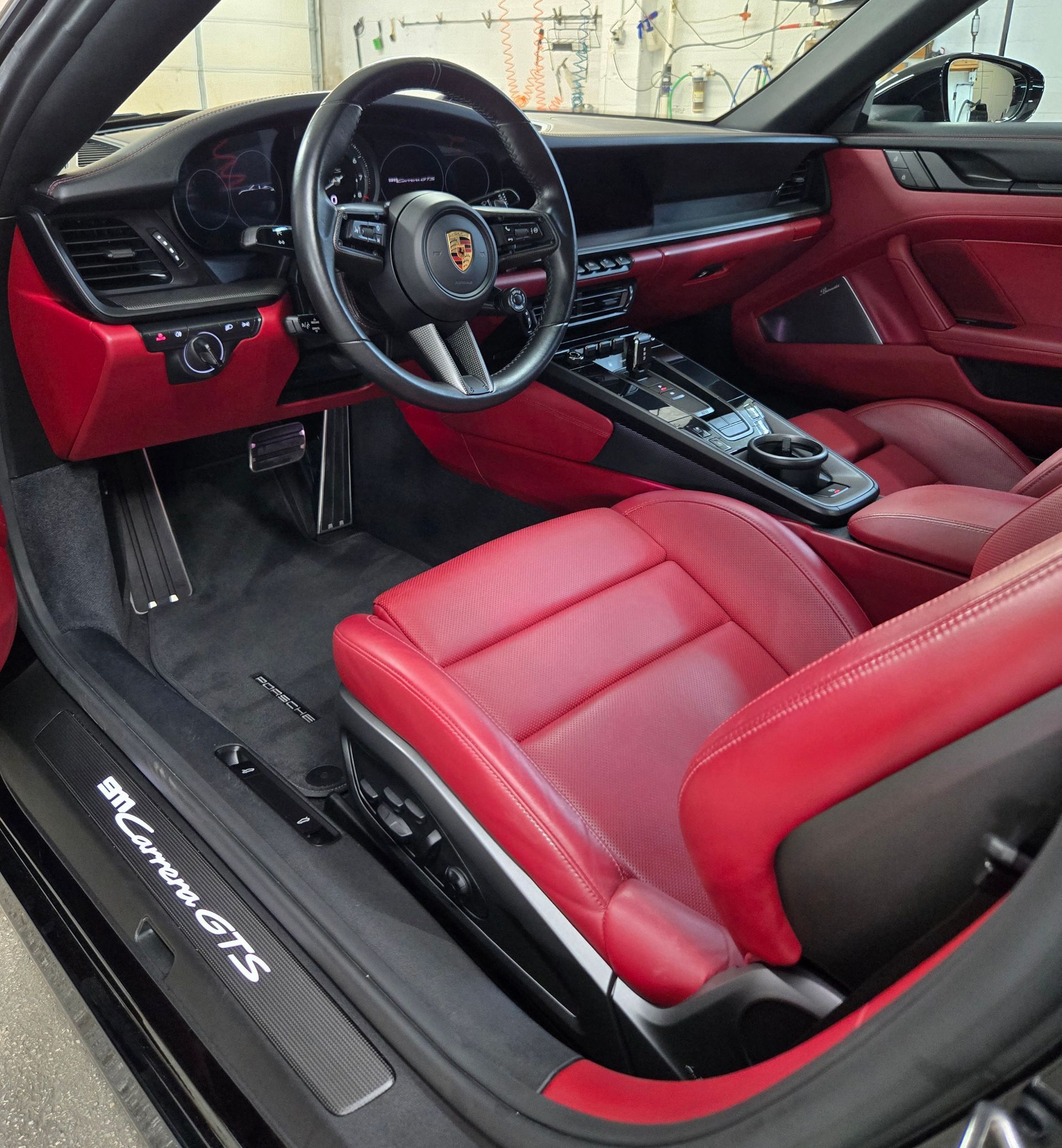 Red leather interior of a black Porsche 911 Carrera GTS.