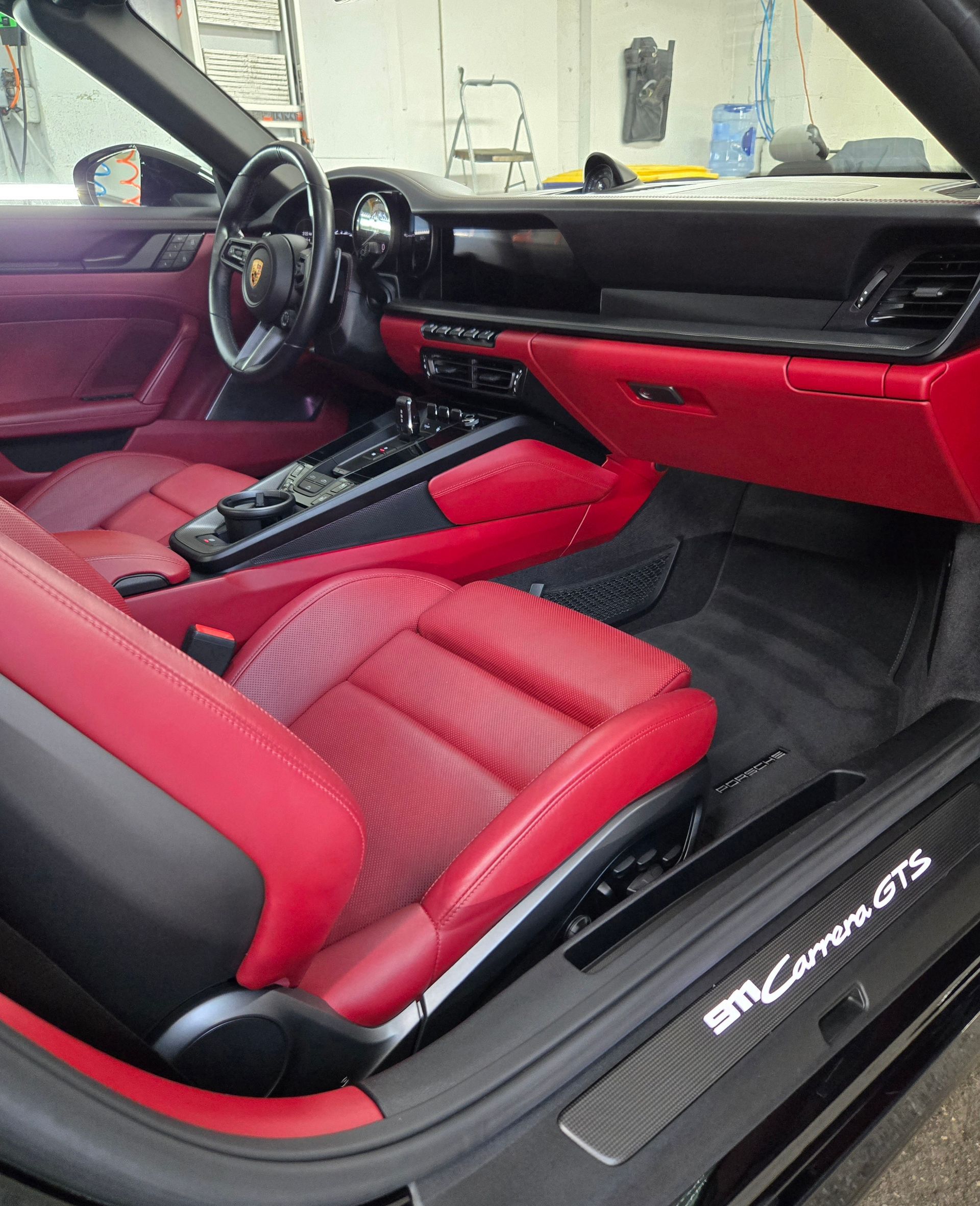 Red leather interior of a black Porsche 911 Carrera GTS.