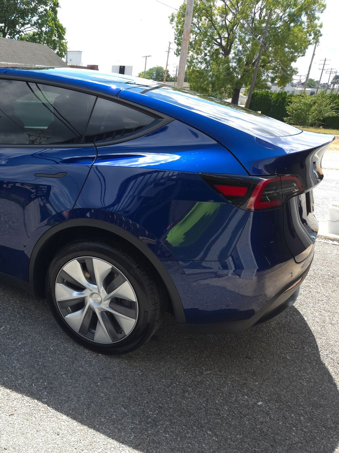 Blue Tesla Model Y parked outside on a sunny day.