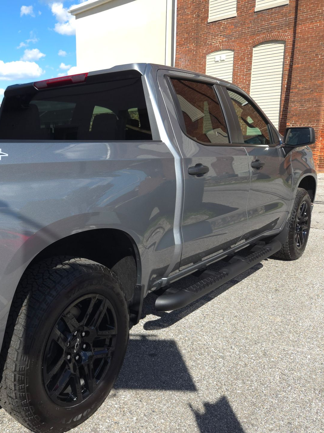 Gray Chevrolet pickup truck with black rims and running boards parked on asphalt.