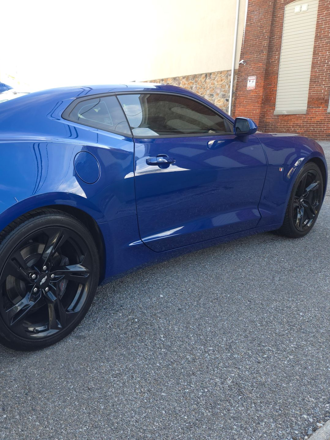 Blue Camaro with black wheels parked on asphalt.