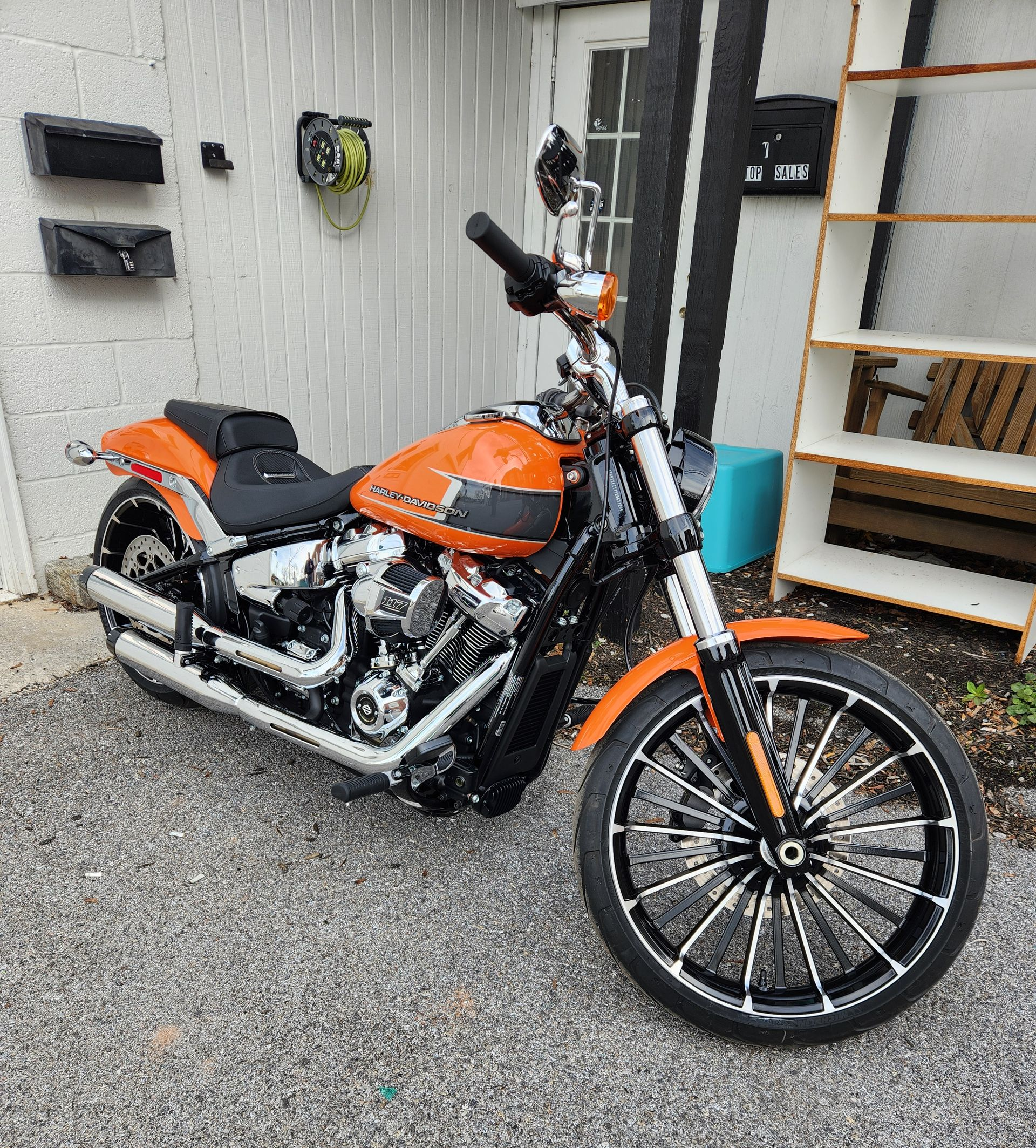 Orange and black Harley-Davidson motorcycle parked on gravel. Includes chrome detailing, black tires and a black seat.