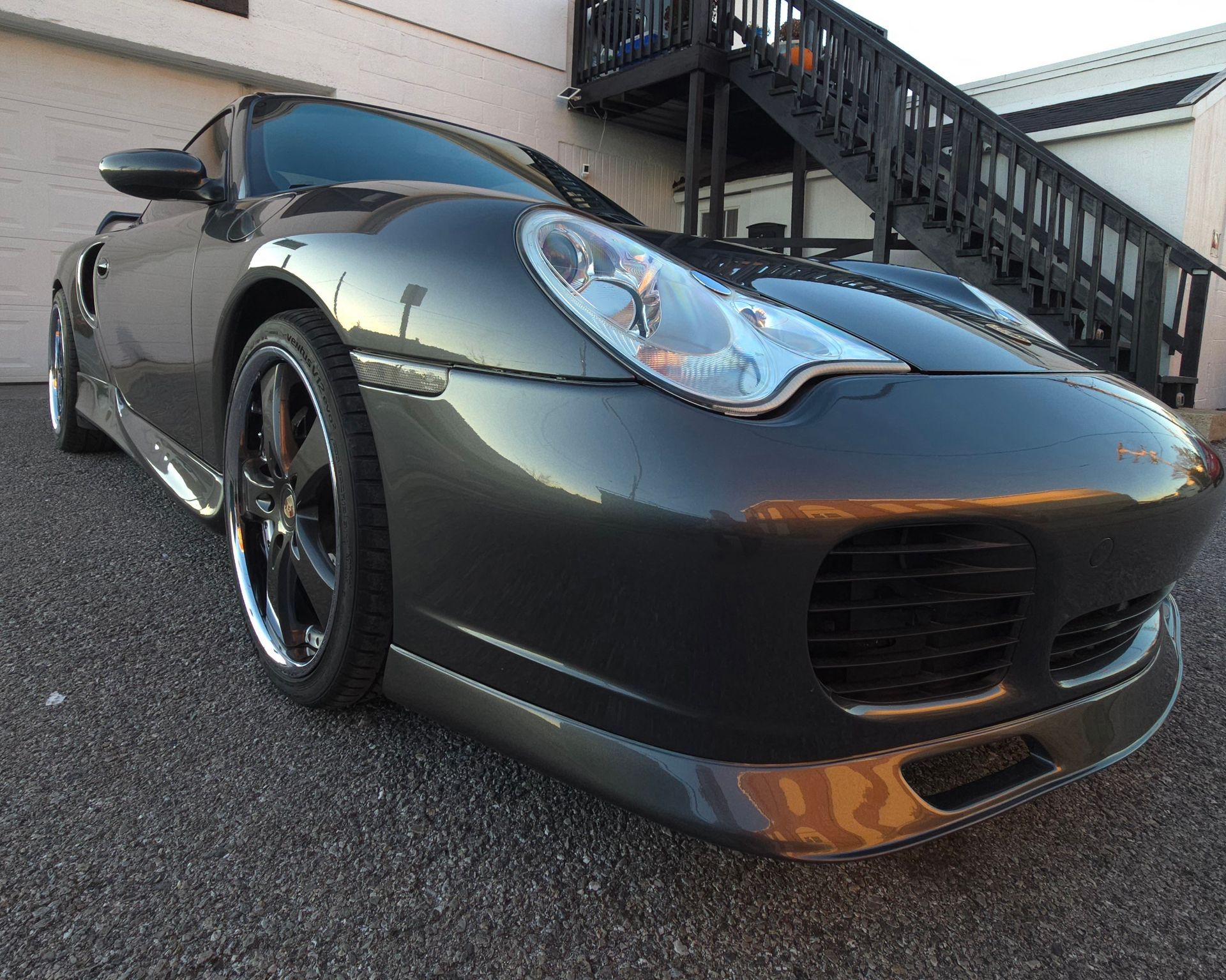 Gray Porsche sports car parked near a building with stairs.