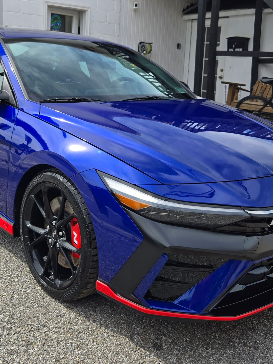 Blue car with black wheels and red accents parked outdoors.