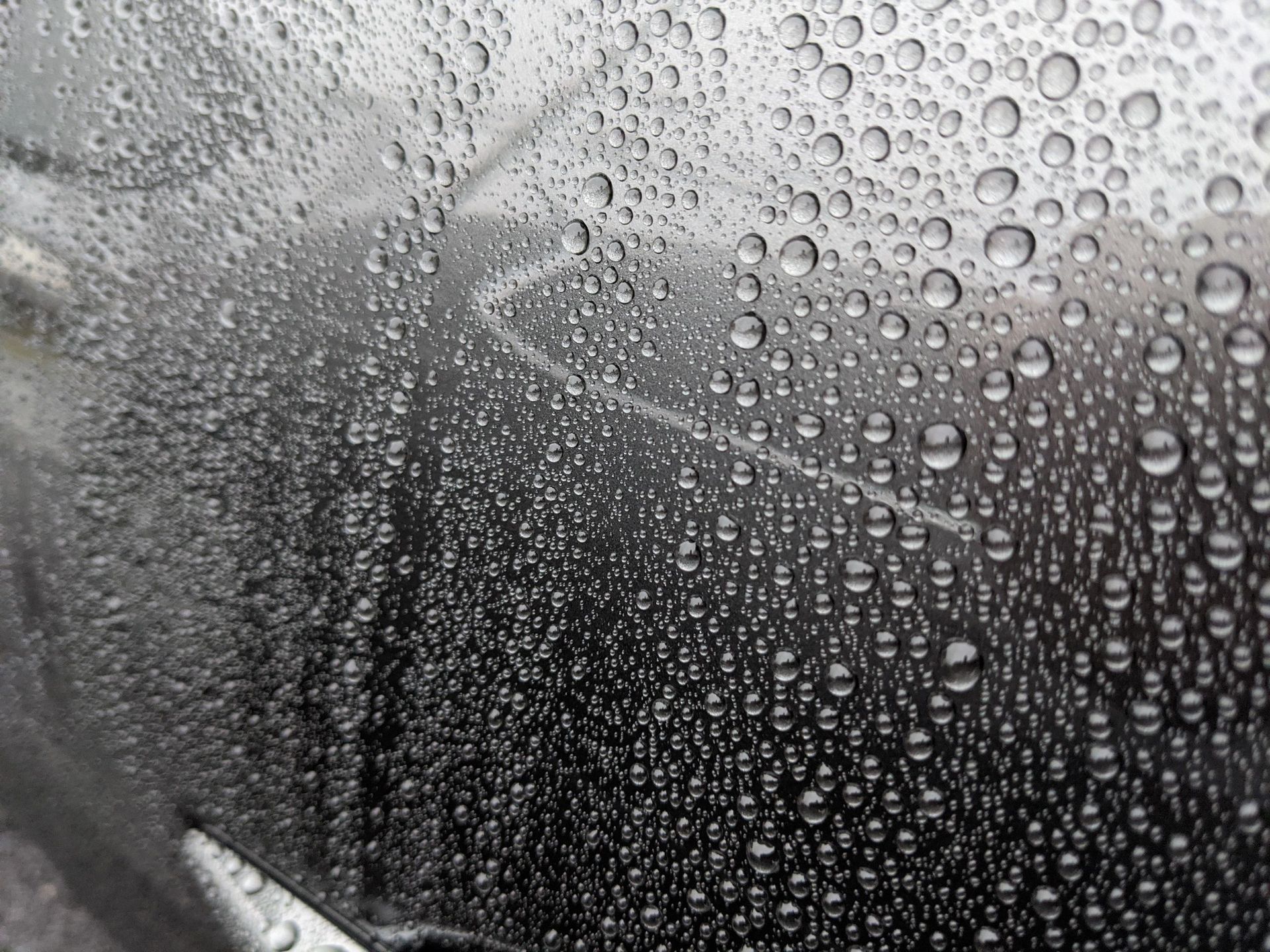 Raindrops on a window obscure a blurry view of a road with a white stripe.