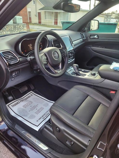 Black Jeep Grand Cherokee interior with leather seats, steering wheel, and digital display.