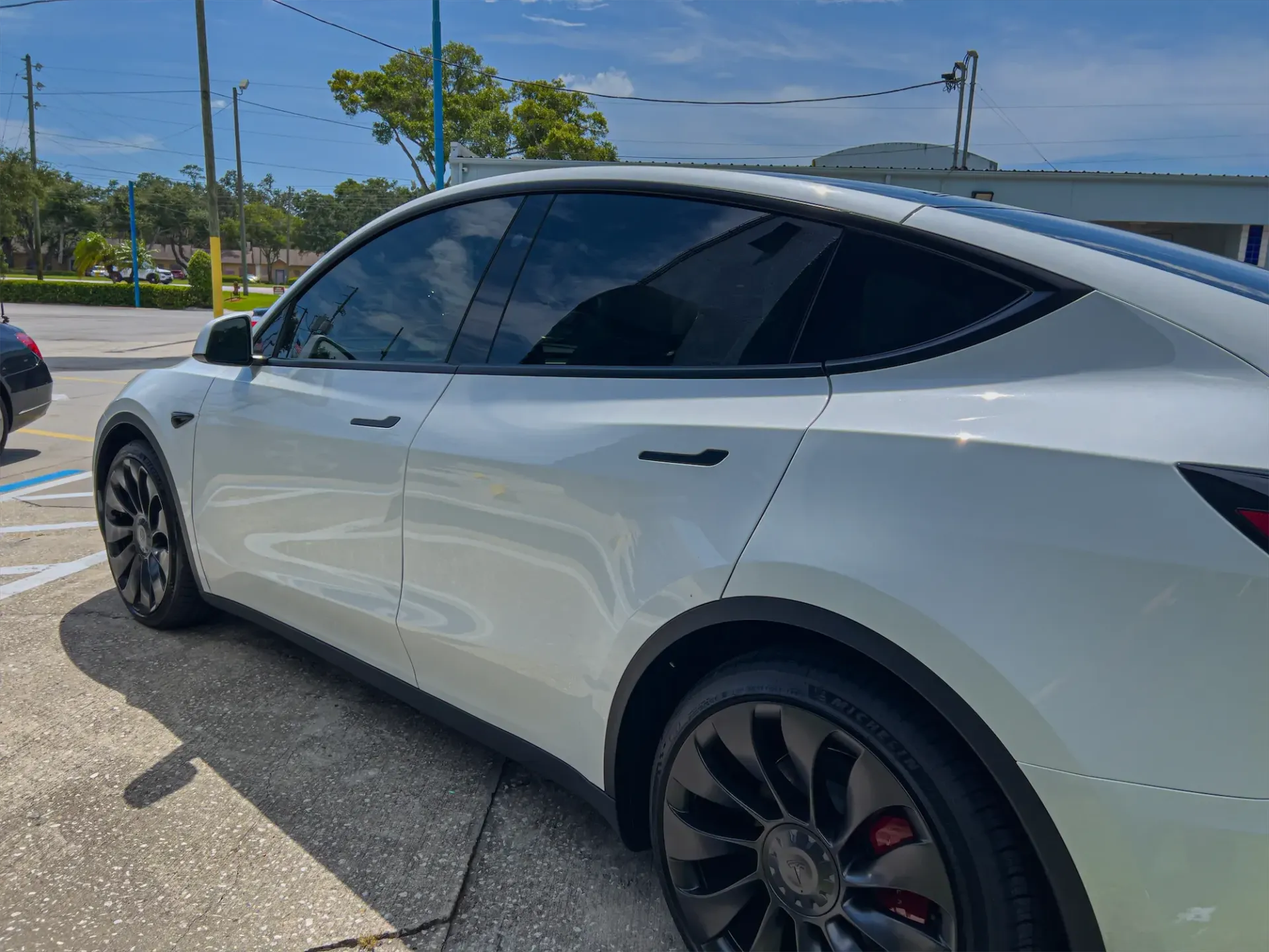 White Tesla Model Y car with tinted windows parked outdoors.