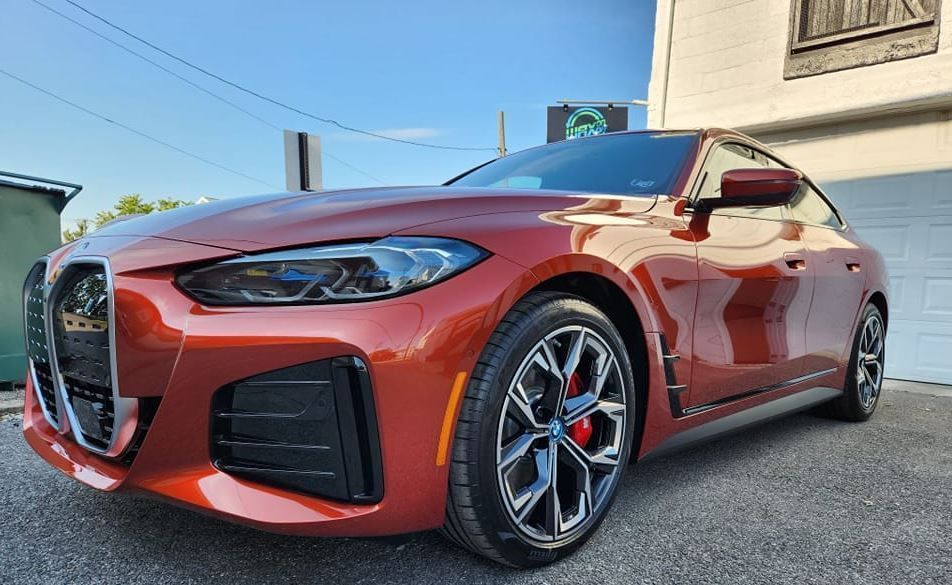 An orange BMW sports car parked on a street on a sunny day.