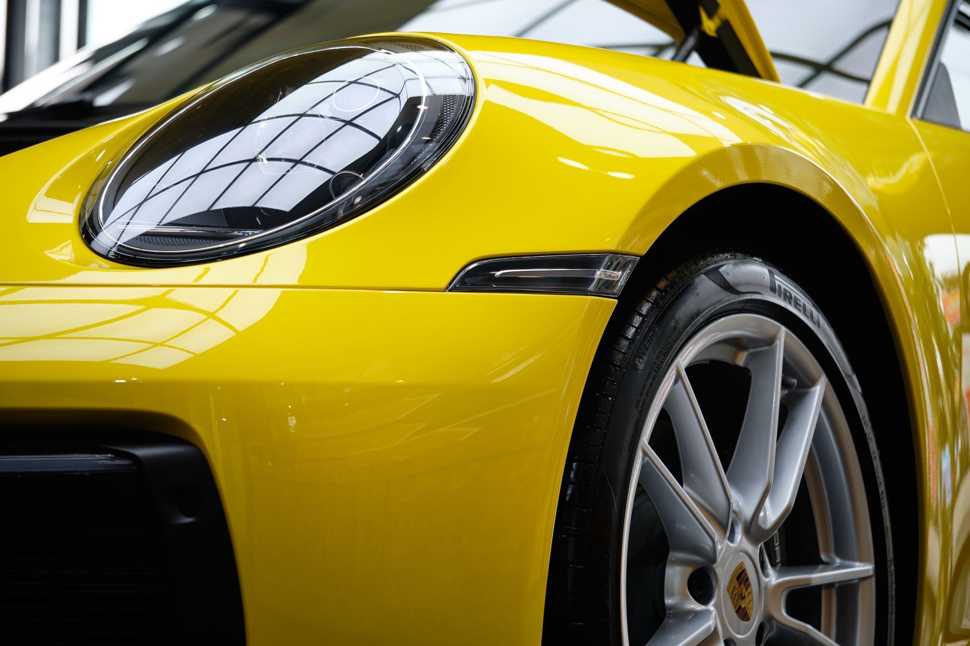 Yellow Porsche sports car, close-up of the front, showing headlight and wheel.