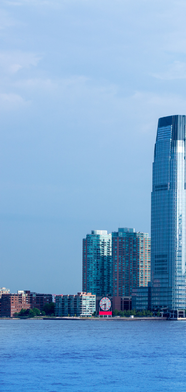 City skyline with skyscrapers and water. Blue sky and water, with some buildings in the foreground.