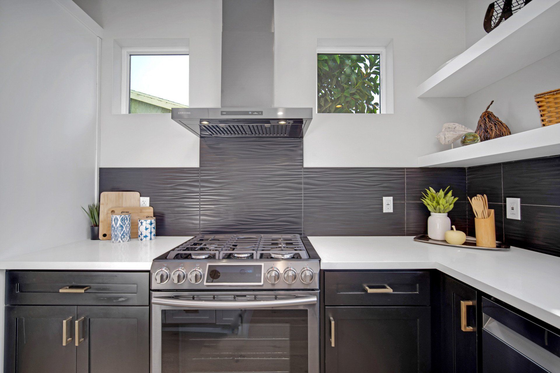 Gleaming countertops set against contrasting grey appointments and shiny chrome electric stove in the full kitchen of an accessory dwelling unit (ADU) granny flat.