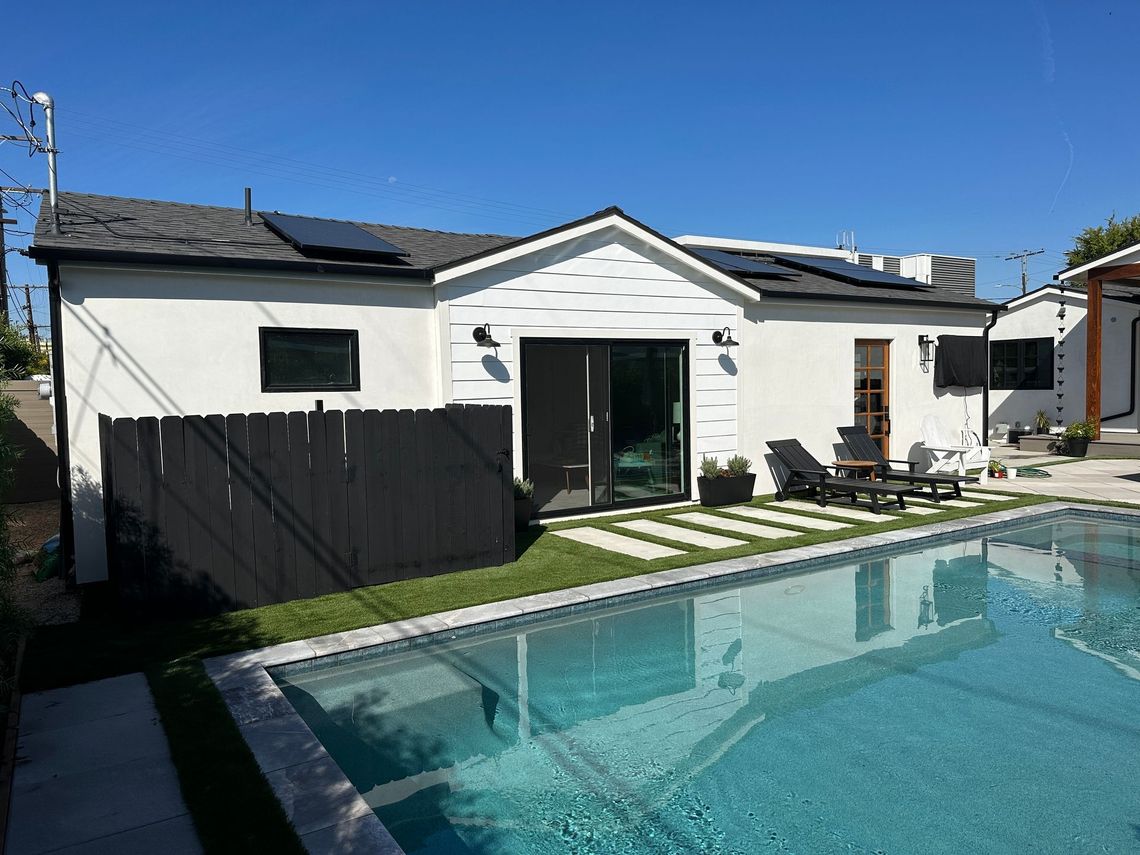 A beautiful, custom-designed accessory dwelling unit (ADU) in-law unit, with sliding glass doors opening up to a backyard pool and patio. 