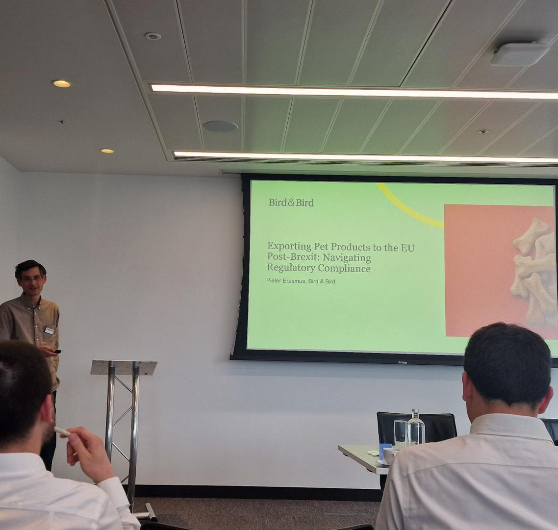 A woman and a man stand smiling in front of a painted mural that says 