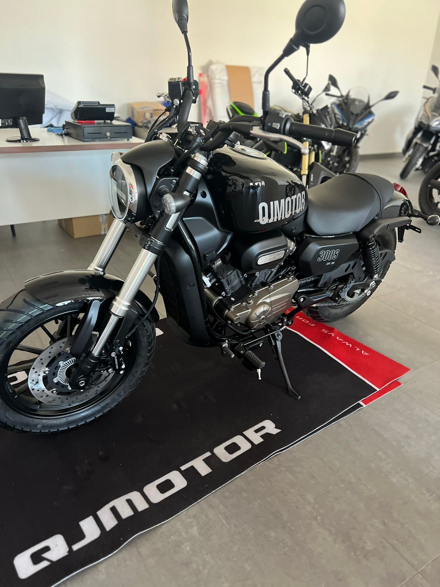 Una moto nera è parcheggiata su un tappetino in uno showroom.