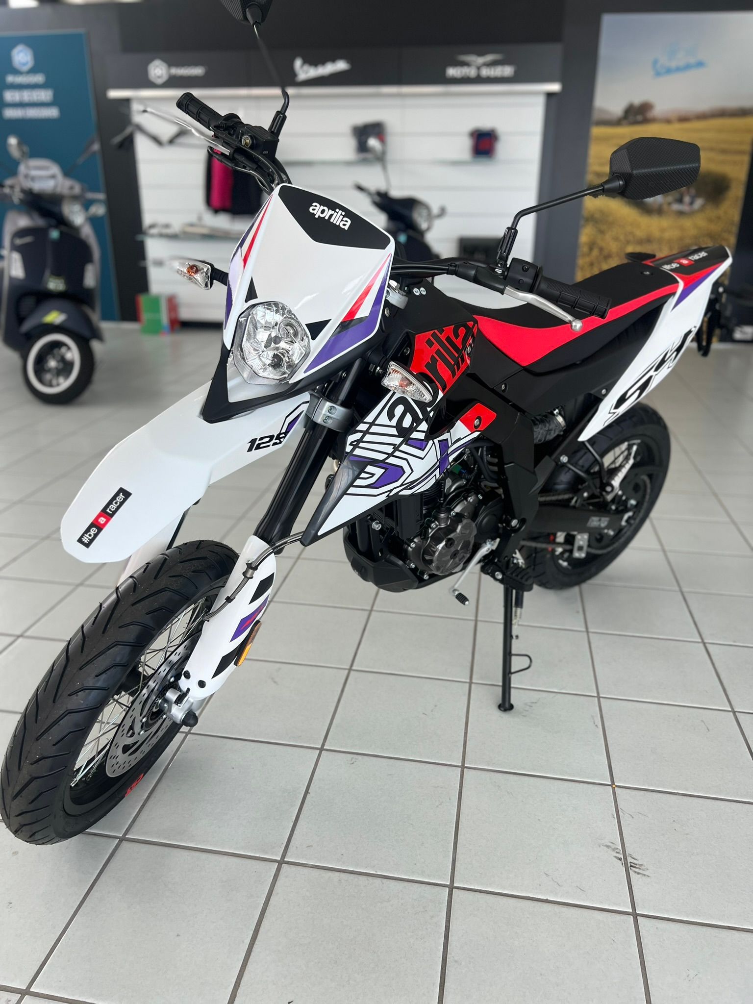 Una moto è parcheggiata su un pavimento piastrellato in uno showroom.