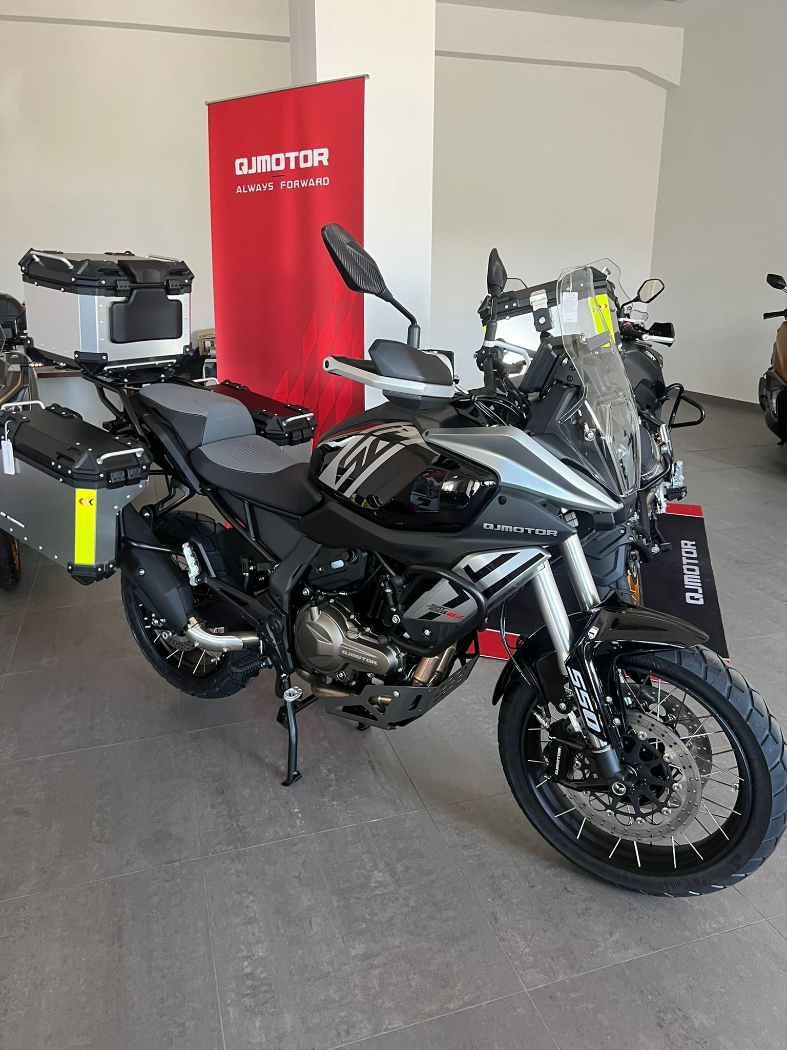 Una moto è parcheggiata in uno showroom accanto a uno striscione rosso.