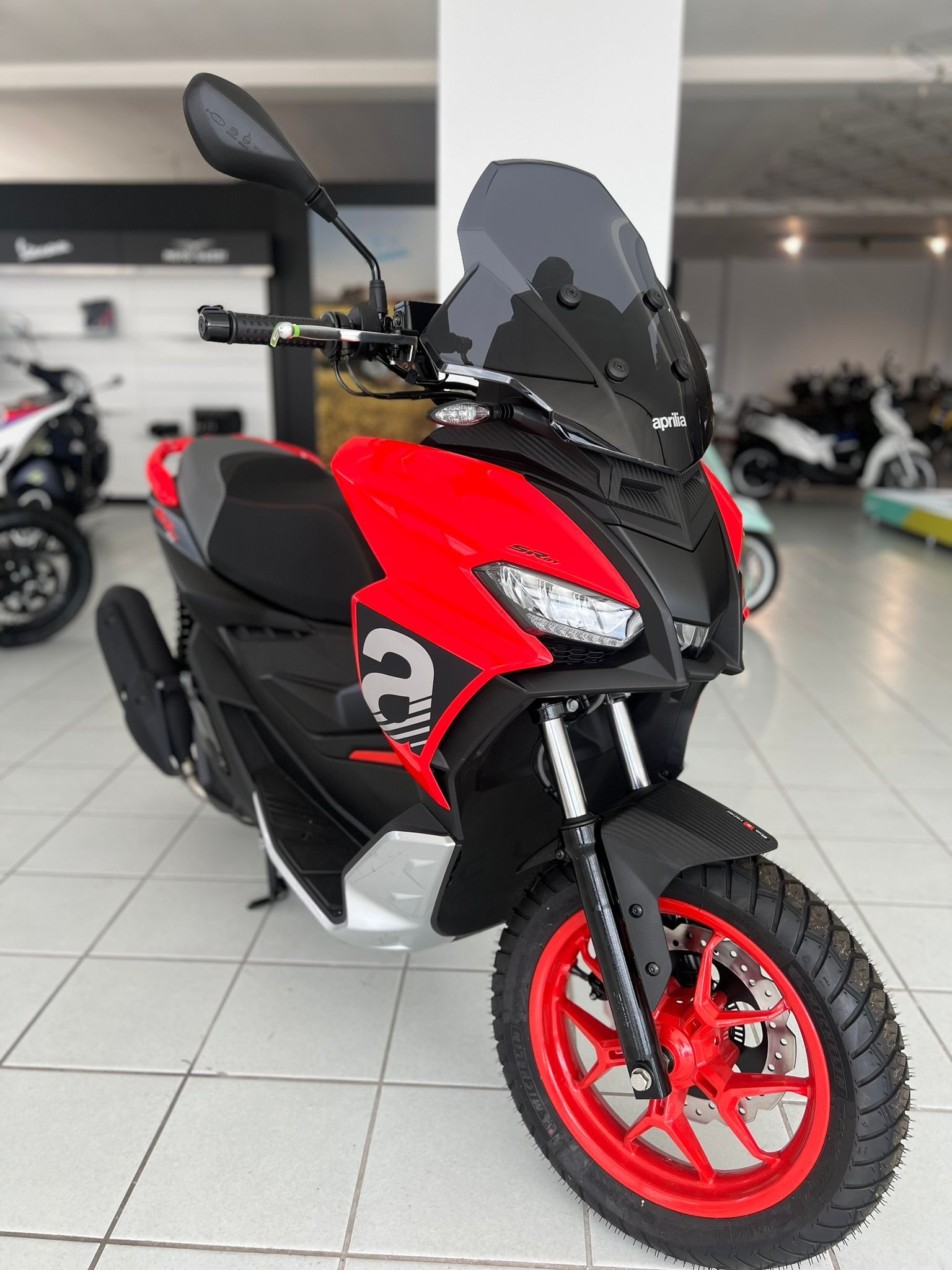 Uno scooter rosso e nero è parcheggiato in uno showroom.