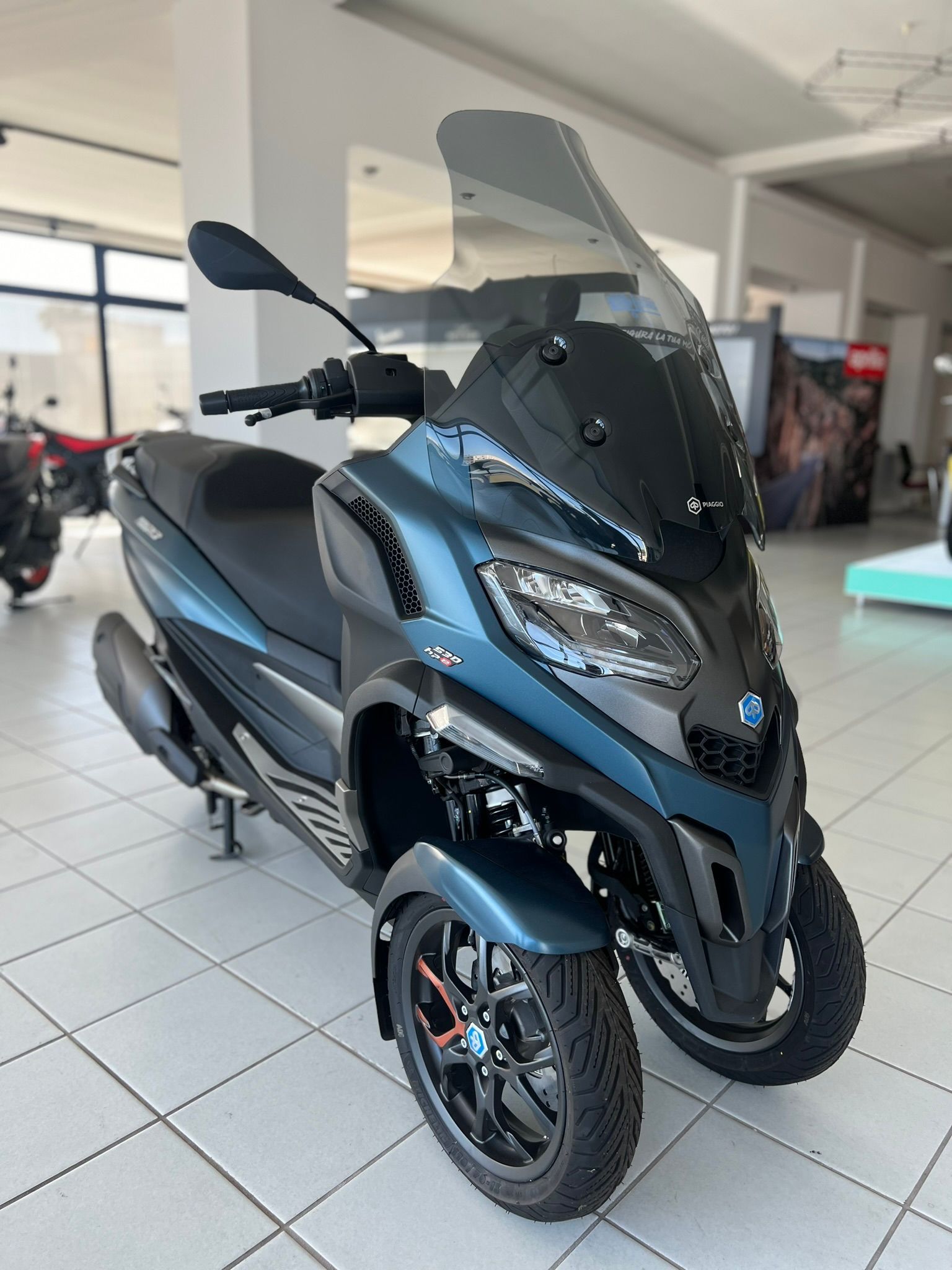 Uno scooter a tre ruote è parcheggiato in uno showroom.