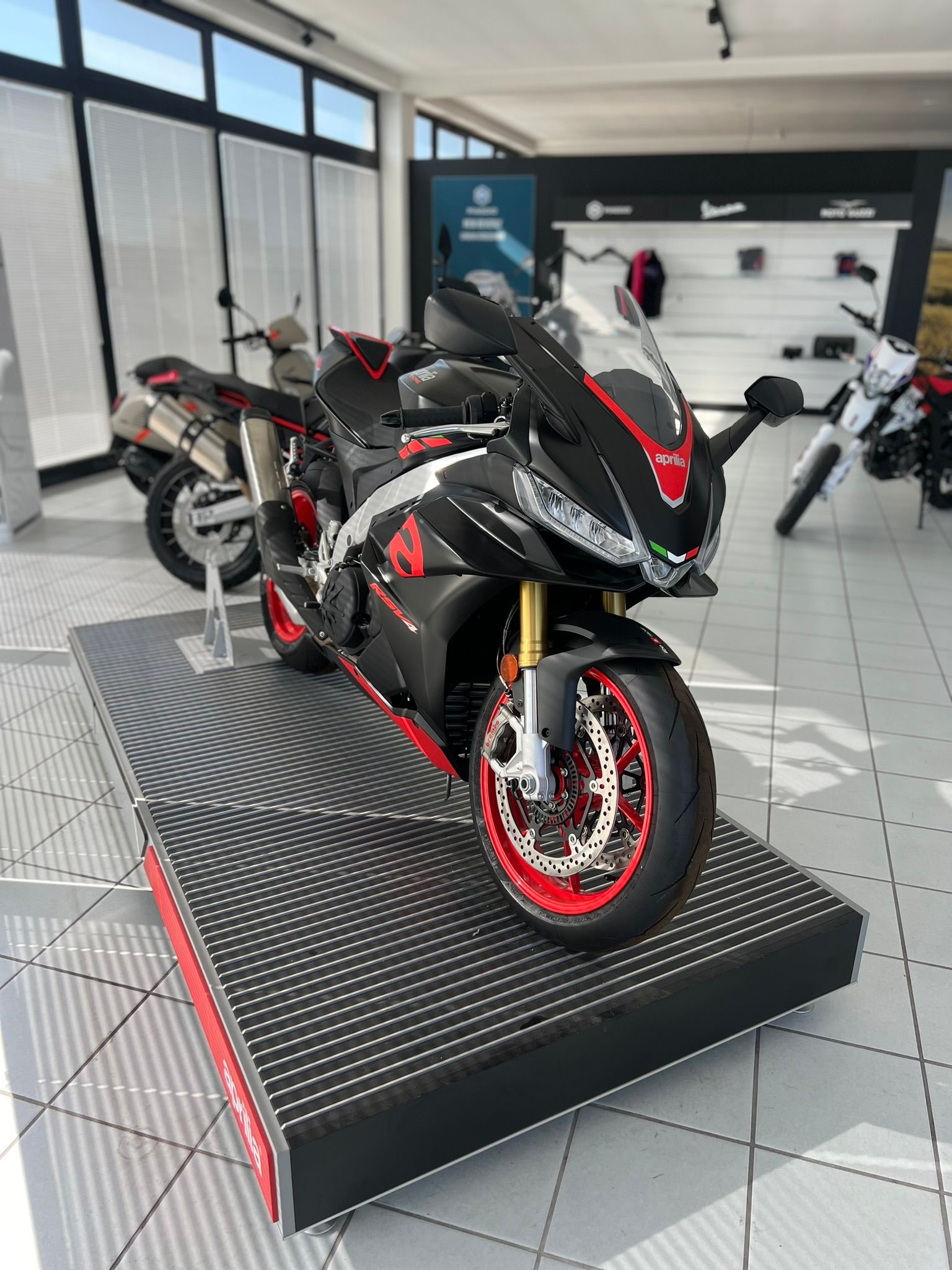 Una moto nera e rossa è esposta in uno showroom.